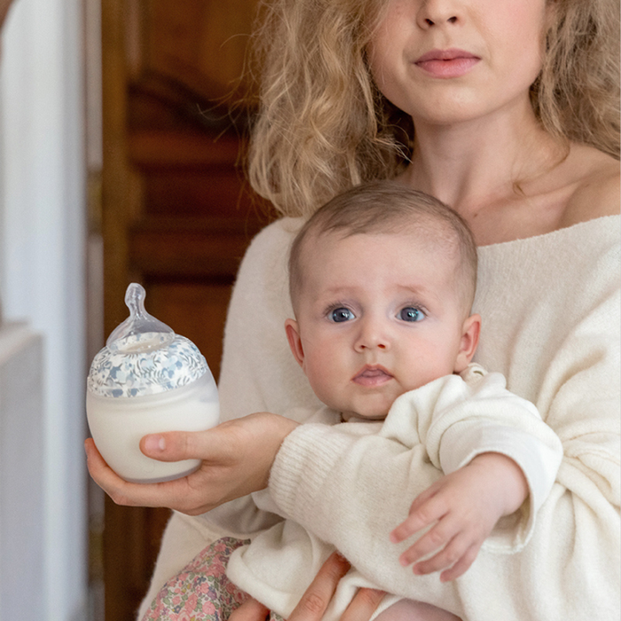 Woman holding a baby and a decorative baby bottle