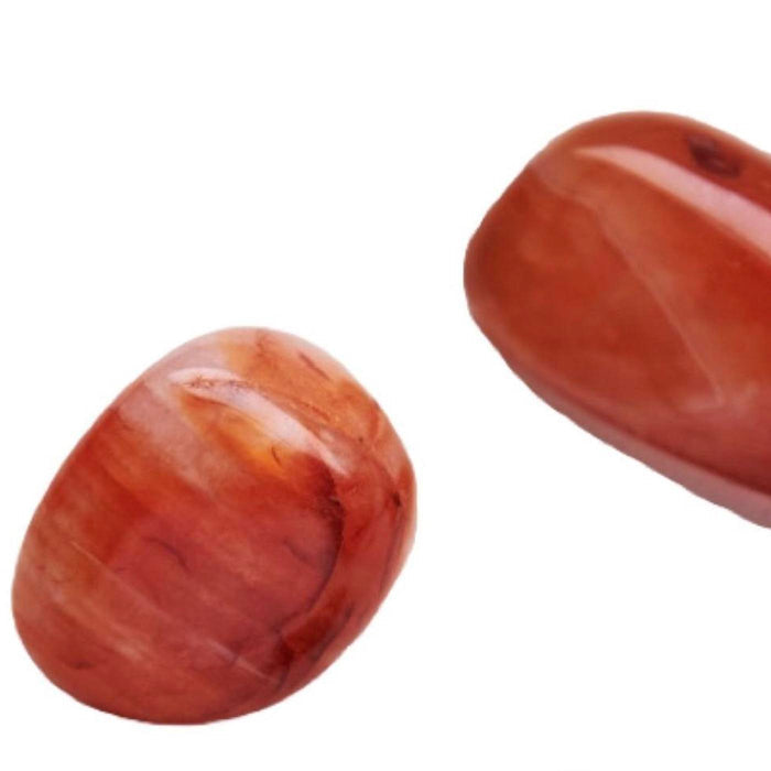 Close-up of two polished reddish stones on a white background, styled to complement the Energy Essential Oil Vial | Aluminate Life for wellness and body care use.