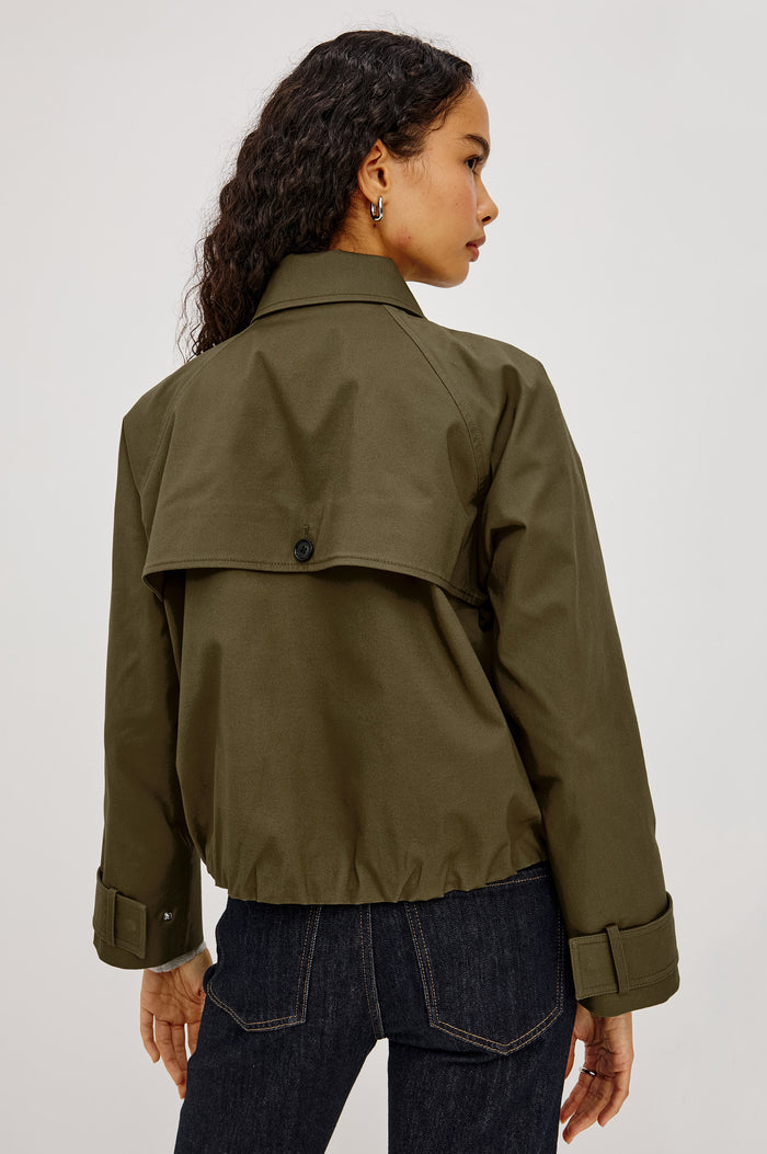 Jett Cropped Trench Jacket in Cotton Garbardine With Double-Breasted Design, Structured Collar, Pockets, and Long Cuffed Sleeves in Olive Colorway - Upper Body Back View Featured on Model