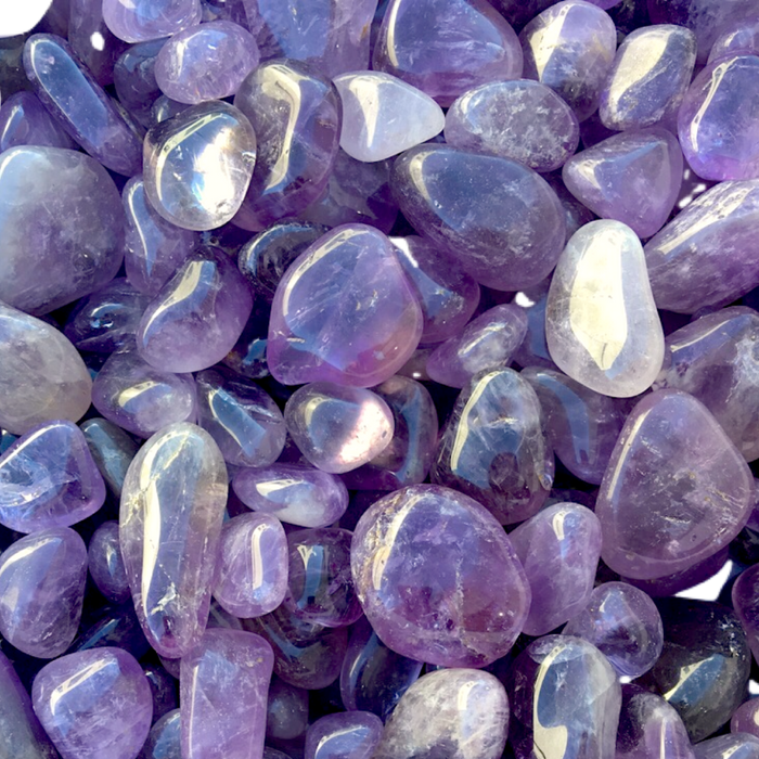 Close-up of polished purple amethyst stones with glossy, smooth surfaces reflecting light, accompanying the Release Candle Tin | Aluminate Life for a calming, wellness-inspired aesthetic.