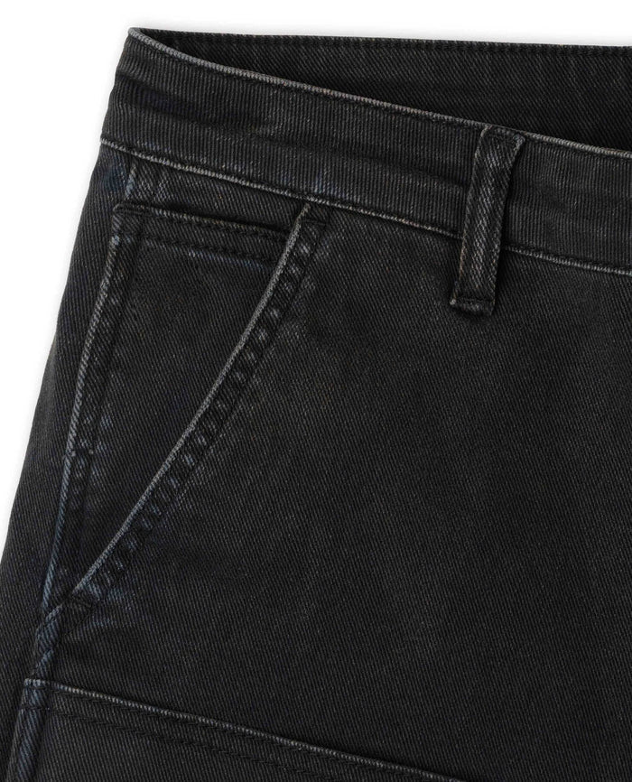 Close-up of black 10-ounce twill utility pants featuring reinforced double-knee panels and deep side pockets.