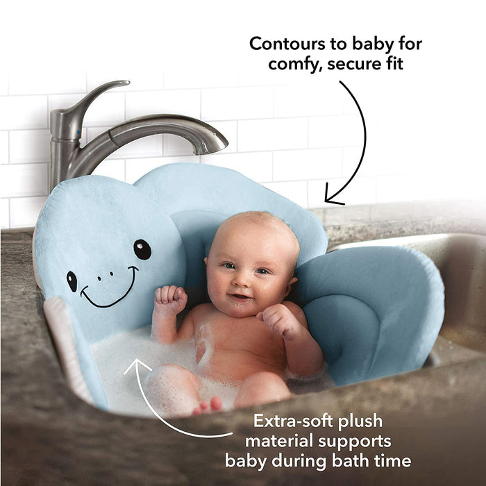 A smiling baby sits in a kitchen sink on the Baby Bath Sink & Tub Cushion, a blue flower-shaped plush bath mat. Arrows highlight its soft material and contouring design, providing comfort for baby during bath time.