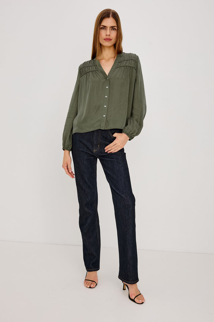 Cadence Shirt in Silky Fabric With Cutaway V-Neck, Shirred Yoke, Front Button Placket, and Slight Puff Long Sleeves and Elastic Cuffs in Washed Olive Colorway - Full Body Front View Featured on Model