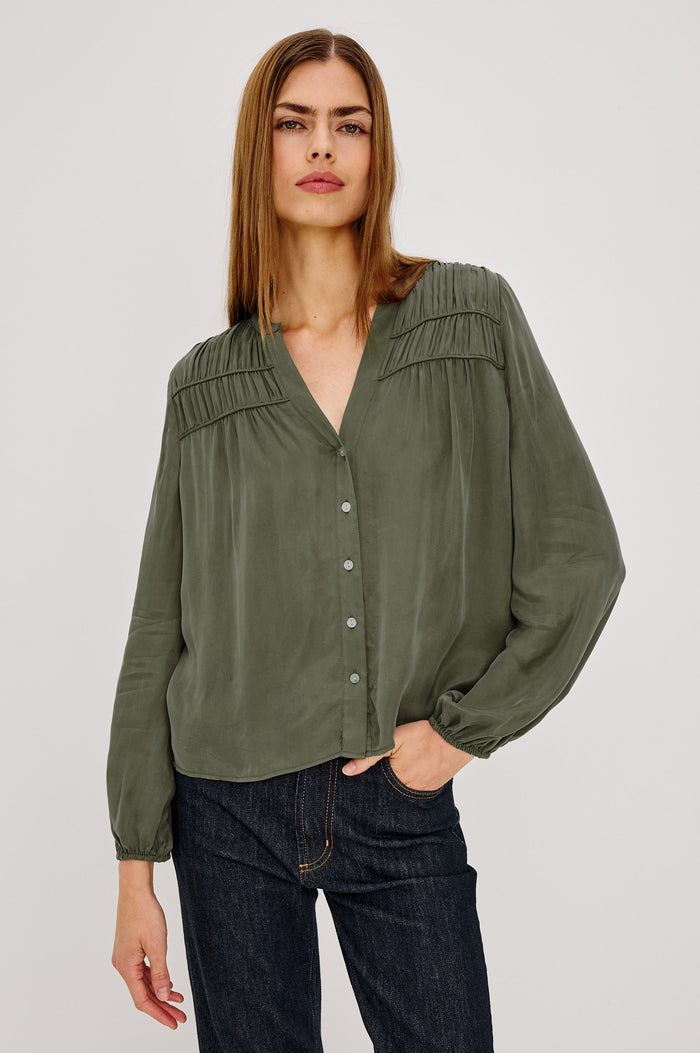 Cadence Shirt in Silky Fabric With Cutaway V-Neck, Shirred Yoke, Front Button Placket, and Slight Puff Long Sleeves and Elastic Cuffs in Washed Olive Colorway - Upper Body Front View Featured on Model