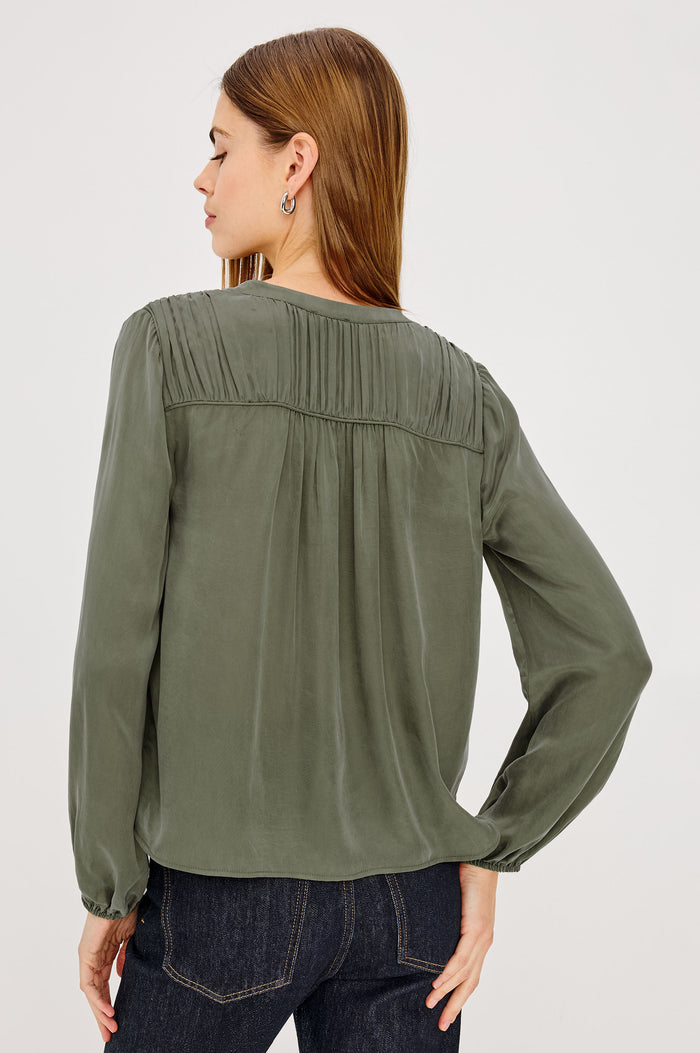 Cadence Shirt in Silky Fabric With Cutaway V-Neck, Shirred Yoke, Front Button Placket, and Slight Puff Long Sleeves and Elastic Cuffs in Washed Olive Colorway - Upper Body Back View Featured on Model