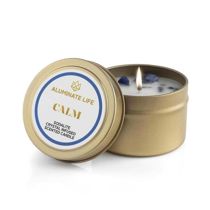 Calm Candle Tin | Aluminate Life featuring a lit scented candle infused with sodalite crystals in a gold travel tin for relaxation and wellness.