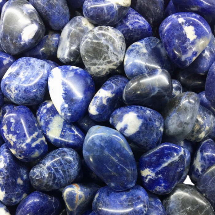 Close-up of polished blue and white stones in a natural arrangement, representing calm and wellness, alongside the Calm Candle Tin | Aluminate Life for a soothing ambiance.