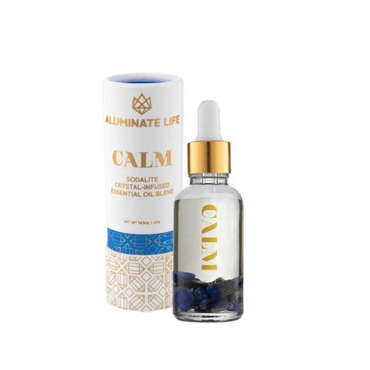 Calm Essential Oil Vial | Aluminate Life featuring a clear glass dropper bottle with blue sodalite crystals inside and a branded white and gold cylindrical packaging for wellness and skincare.
