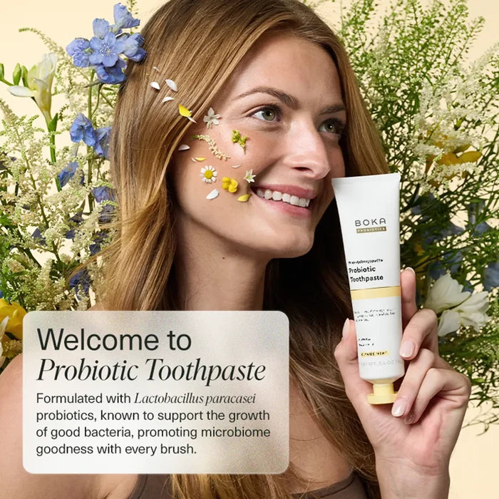 Woman holding a tube of Boka Probiotic Toothpaste with flowers around her.