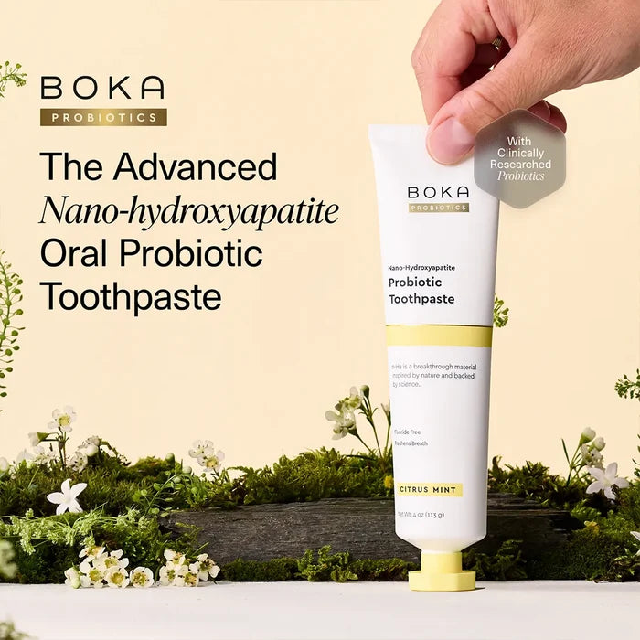 Boka Probiotics toothpaste tube with a hand holding it, against a natural background with plants and flowers.