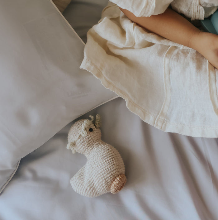 Knitted toy on a bed with a child's legs in the background