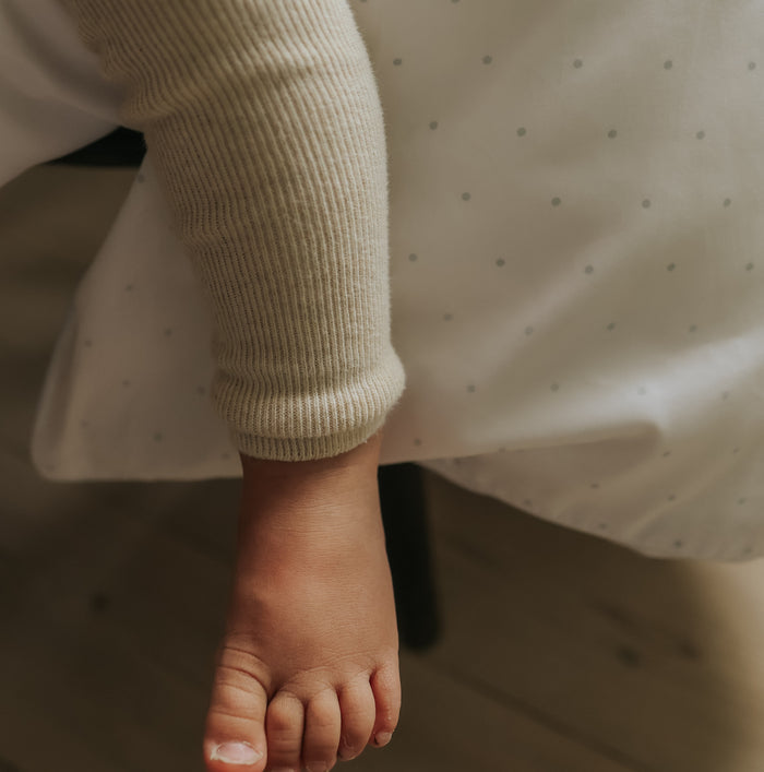Child's bare foot with a light-colored sock on a wooden floor