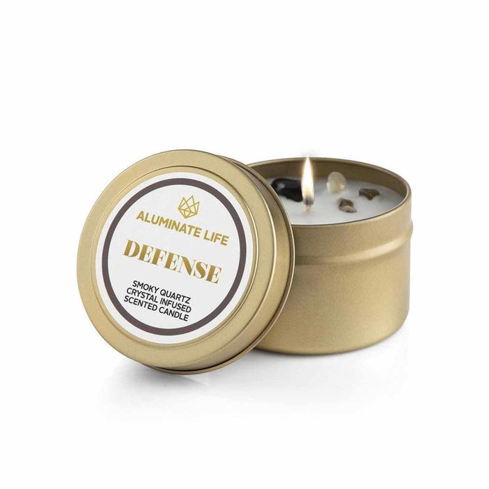 Defense Candle Tin | Aluminate Life featuring a lit gold tin candle infused with smoky quartz crystals, designed for wellness and body care ambiance.