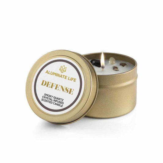 Defense Candle Tin | Aluminate Life featuring a lit gold tin candle infused with smoky quartz crystals, designed for wellness and body care ambiance.