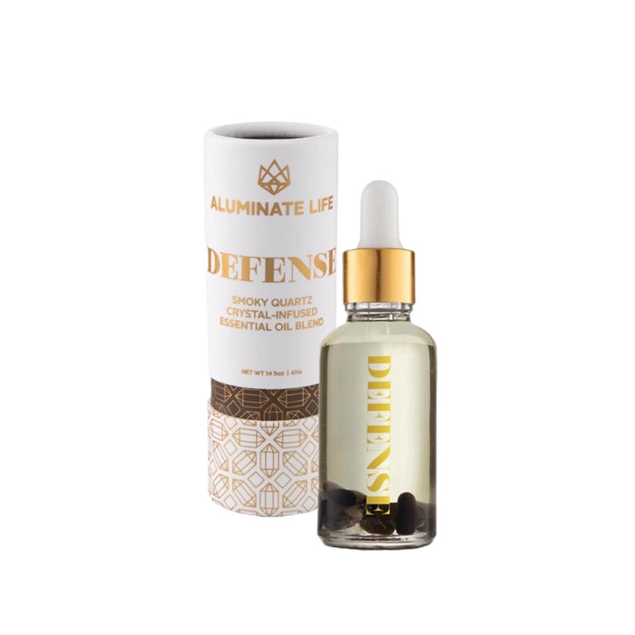 Defense Essential Oil Vial | Aluminate Life with smoky quartz crystal-infused essential oil blend in a clear glass dropper bottle alongside its decorative cylindrical packaging designed for wellness and skincare.