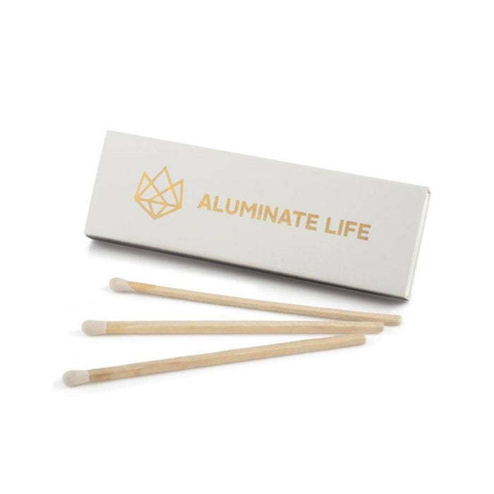Box of matches with three wooden-tipped matches laid out, branded with Aluminate Life logo, shown as part of the Defense Glass Candle | Aluminate Life product set.