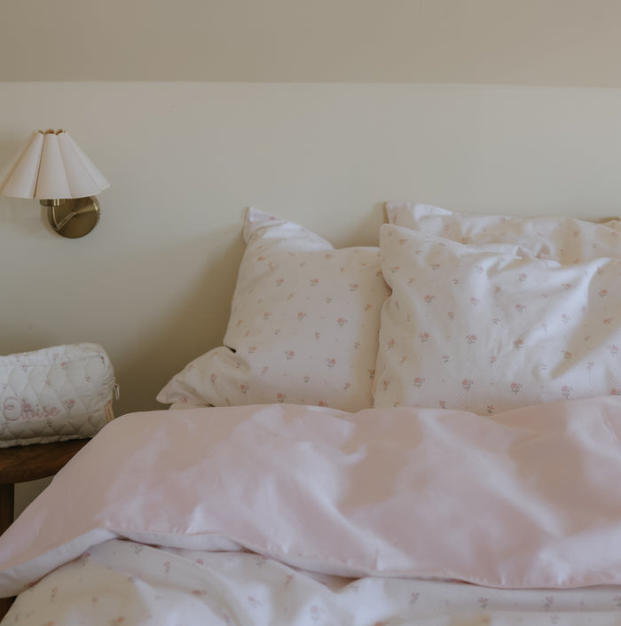 Bed with floral bedding and pillows in a bedroom setting.