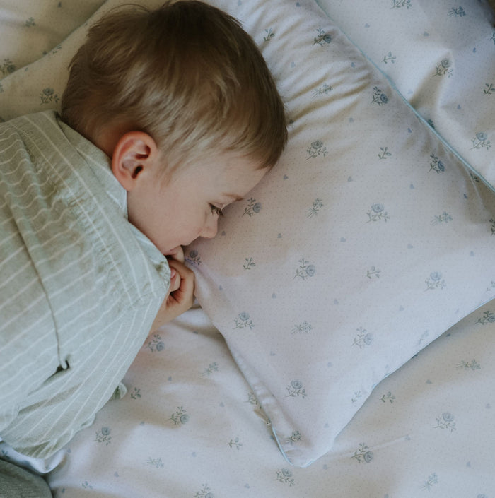 Child sleeping on a floral-patterned pillow and blanket