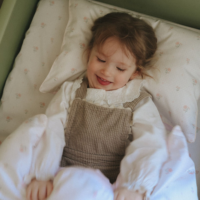 Young girl lying in bed with pink floral bedding and floral pillowcase