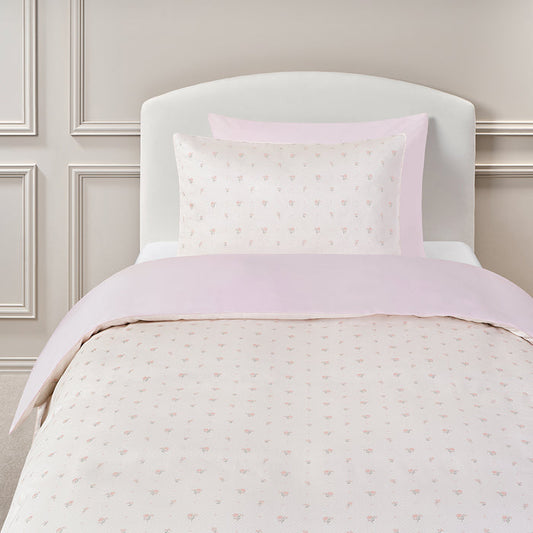 Twin bedding set in the pattern Ditsy Floral in Pink on a bed with a white headboard.
