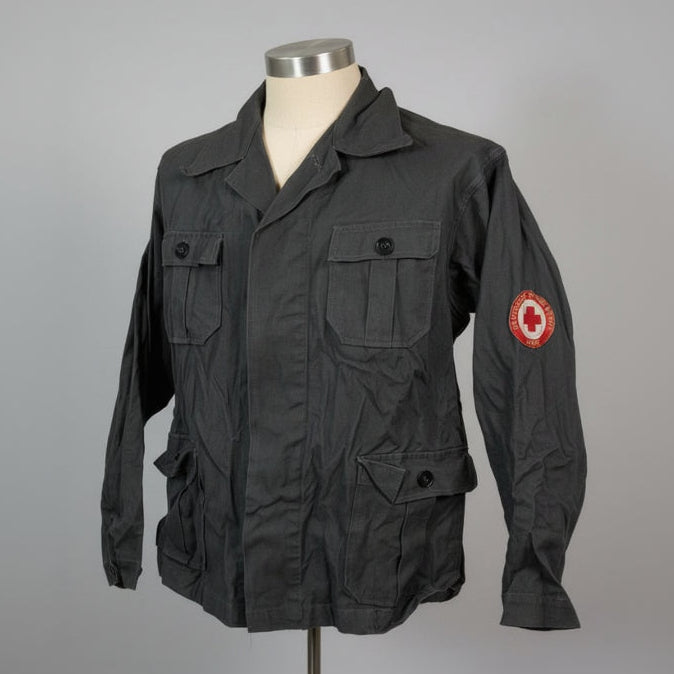 Black jacket with a red cross emblem on a mannequin against a gray background