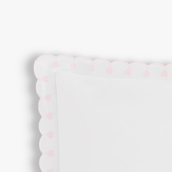 White pillow with pink heart patterns on a white background