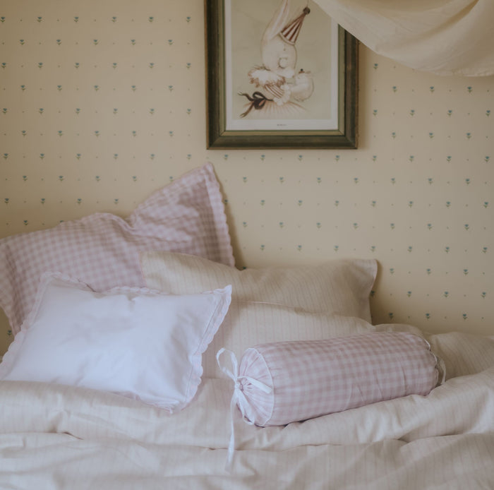 Bed with checkered pillows and a framed picture on the wall
