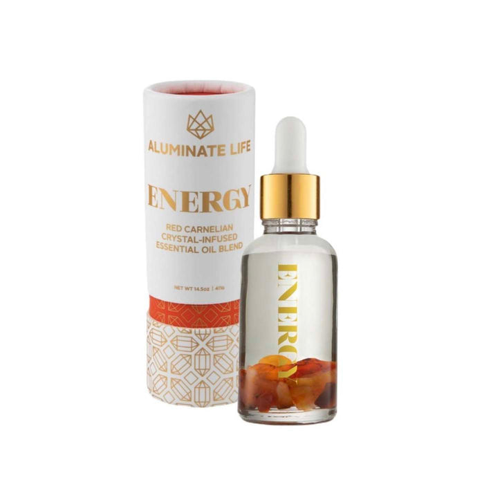 Clear glass dropper bottle with golden cap containing a crystal-infused oil blend next to a white and gold decorative cylindrical box labeled Energy Essential Oil Vial | Aluminate Life.