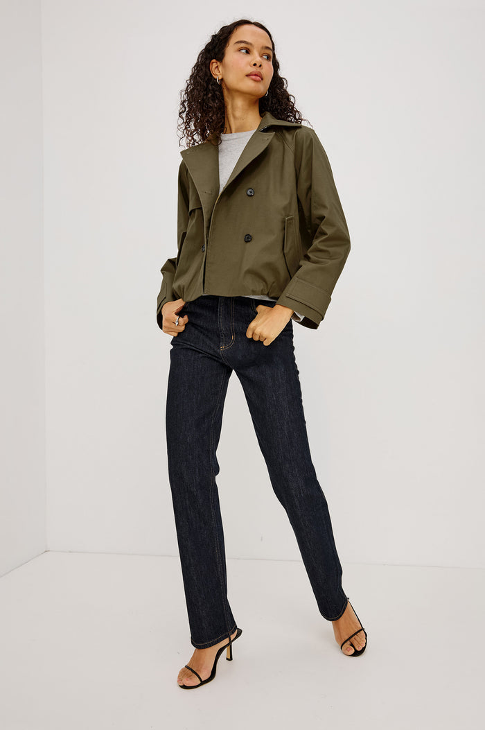 Jett Cropped Trench Jacket in Cotton Garbardine With Double-Breasted Design, Structured Collar, Pockets, and Long Cuffed Sleeves in Olive Colorway - Full Body Front View Featured on Model