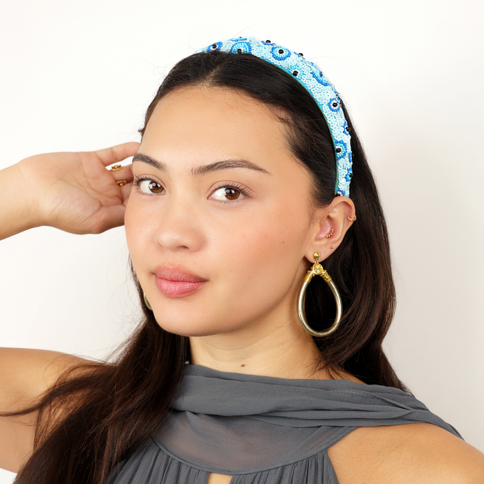 a woman with a blue headband and earrings