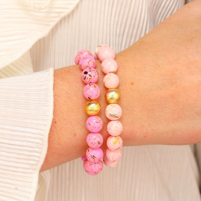 a person wearing pink and gold bracelets