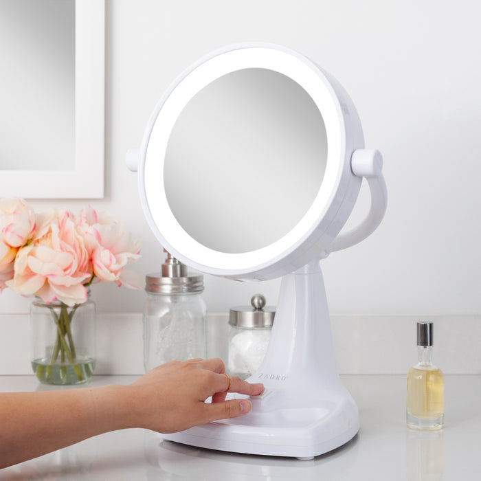 Zadro MAX110 705004420549 environment photo side view user touching power switch, max bright lighted makeup mirror with magnification & storage tray in front of a real life setting