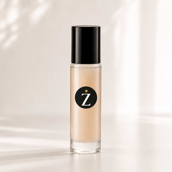 A clear cylindrical bottle of liquid foundation with a black cap, filled with beige makeup, standing on a white surface against a softly lit white background with subtle shadow patterns.