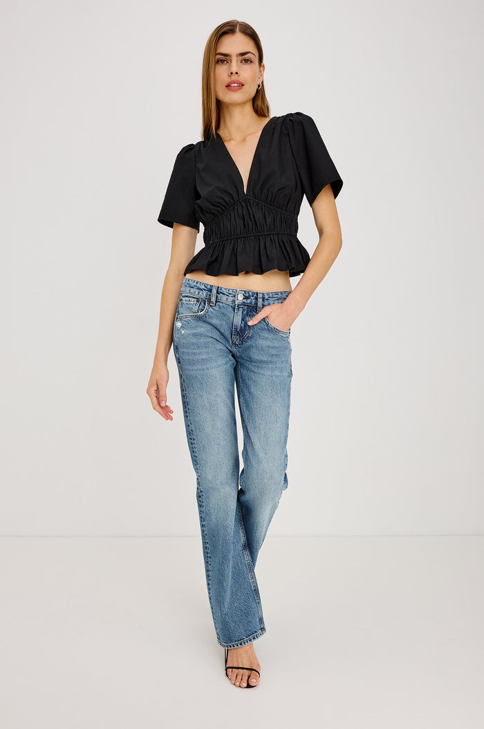 Orla Shirt in Cotton Poplin With Short Puff Sleeves, Deep V-Neckline, Shirred Shoulders, Elastic Waist and Underbust, and Peplum Hem in Black Colorway - Full Body Front View Featured on Model