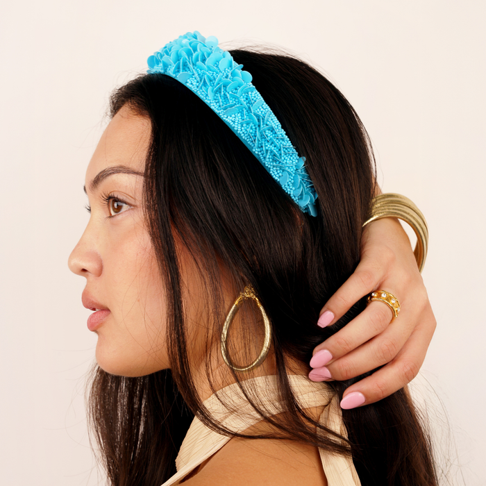 a woman with a blue headband and gold hoop earrings