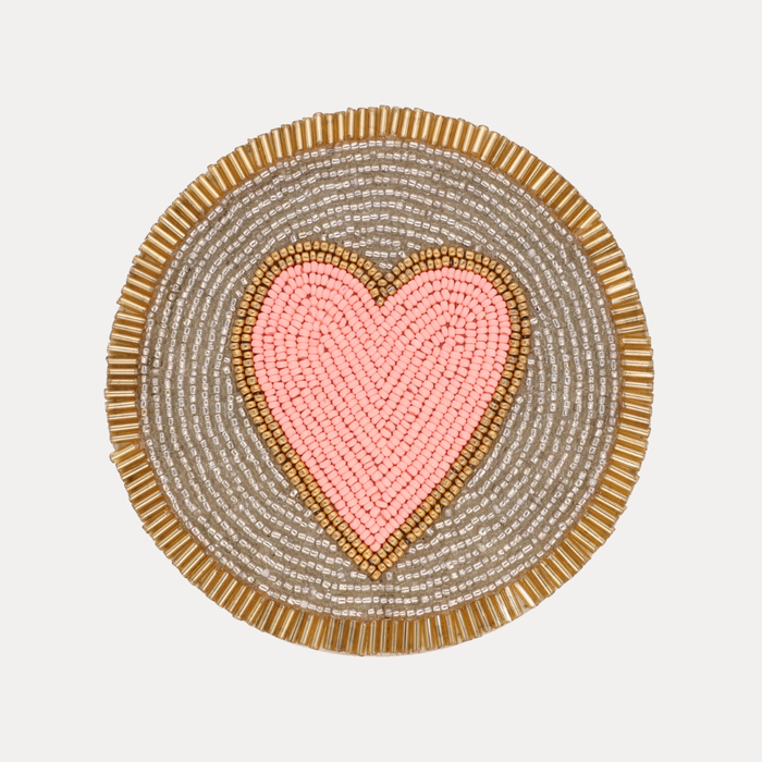a pink heart on a grey and gold circle