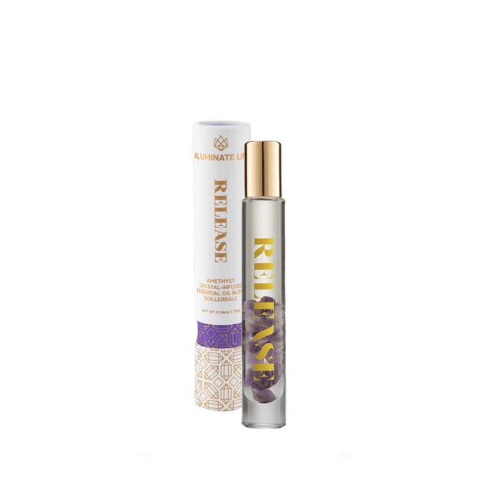 Release Essential Oil Rollerball | Aluminate Life with amethyst crystals inside a clear glass bottle and a gold cap, accompanied by its decorative white and purple cylindrical packaging.