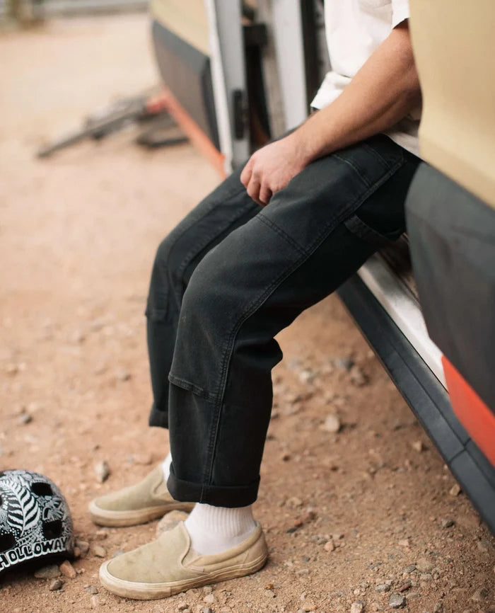 Black RIPTON men's twill utility pants with double-knee panels and relaxed fit, worn while sitting outdoors.