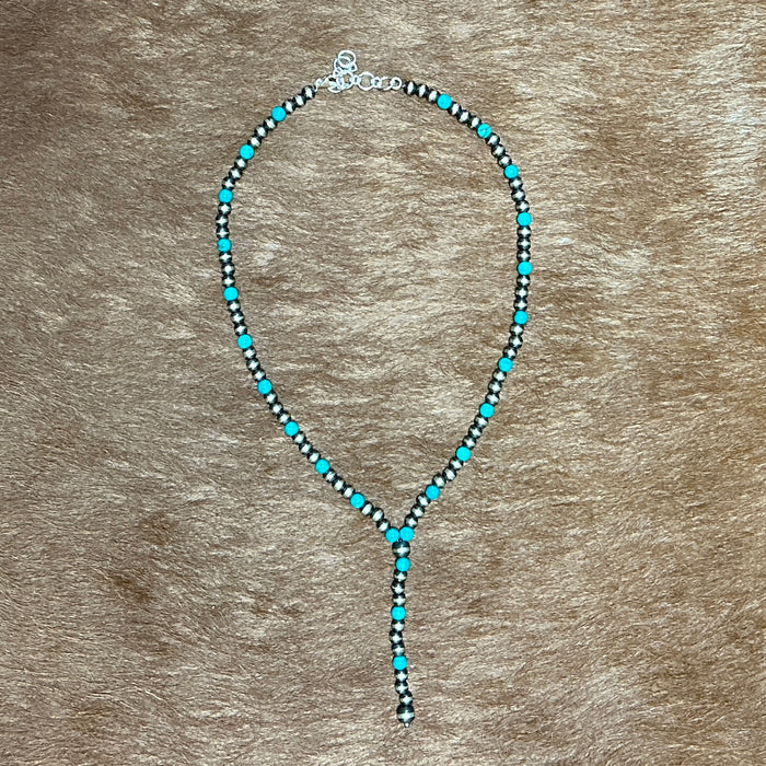 Necklace with turquoise beads on a brown background.