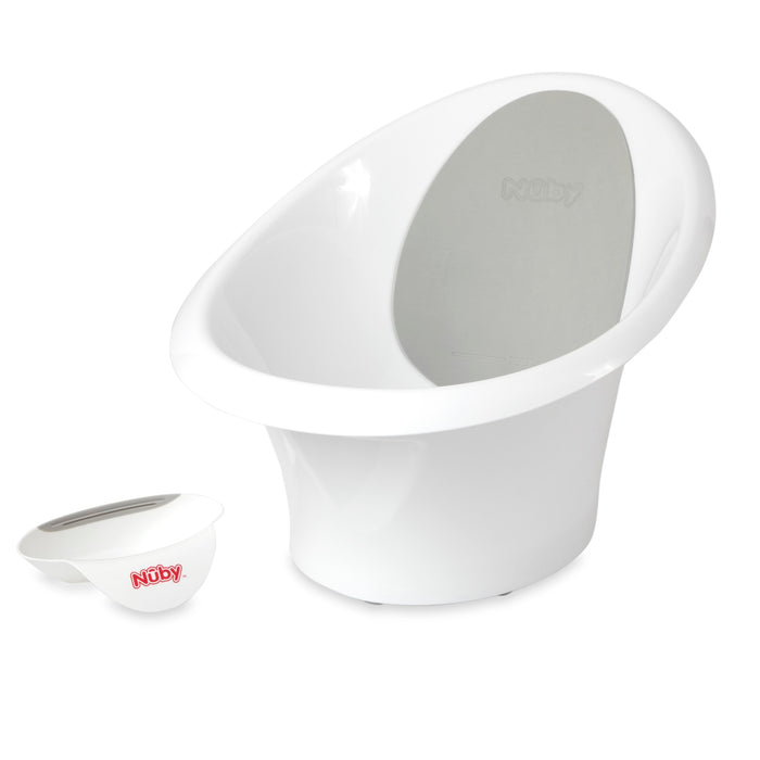 The Sit and Bathe Compact Bathtub is white with a high backrest and gray padding, shown beside a matching white rinse cup with handle. Both display the red Nuby Sit and Bathe logo on a plain white background.