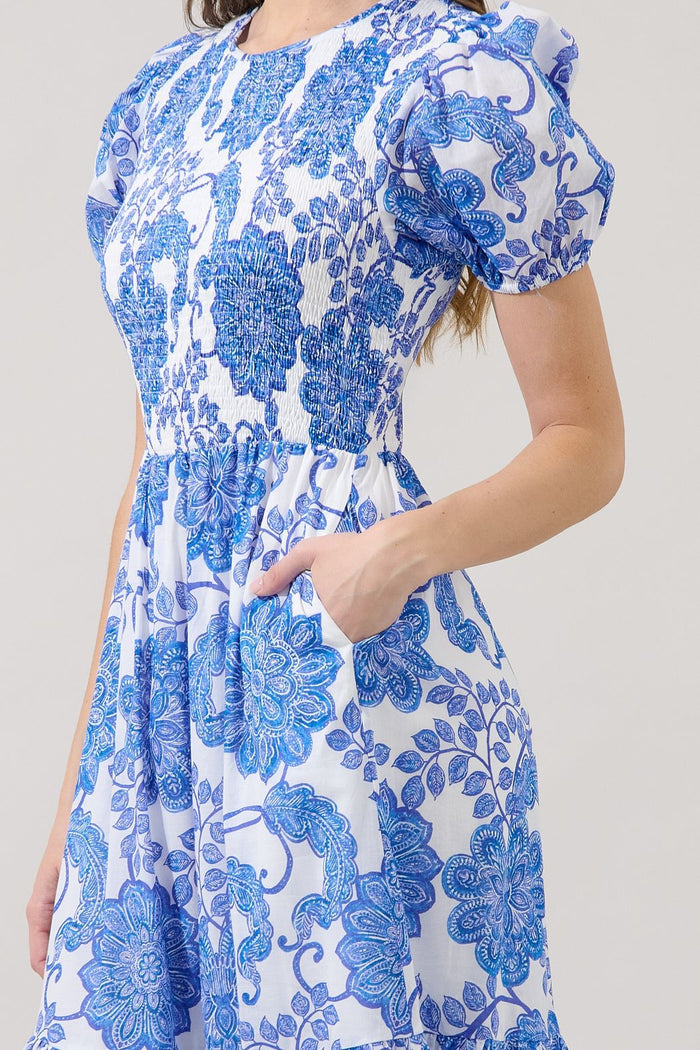 Close-up of blue and white floral Sugarlips smocked midi dress showing puff sleeve, elastic bodice, pocket, and porcelain print.