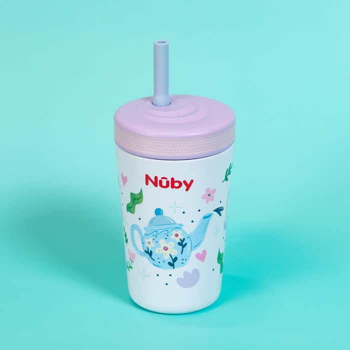 The Nuby Thirsty Kids Flexstraw Stainless Steel Cup | Teapots is a white, no-spill kids cup with a lavender lid, blue teapot design, flowers, and the red Nuby logo—great for cold drinks. Shown on a light blue background.