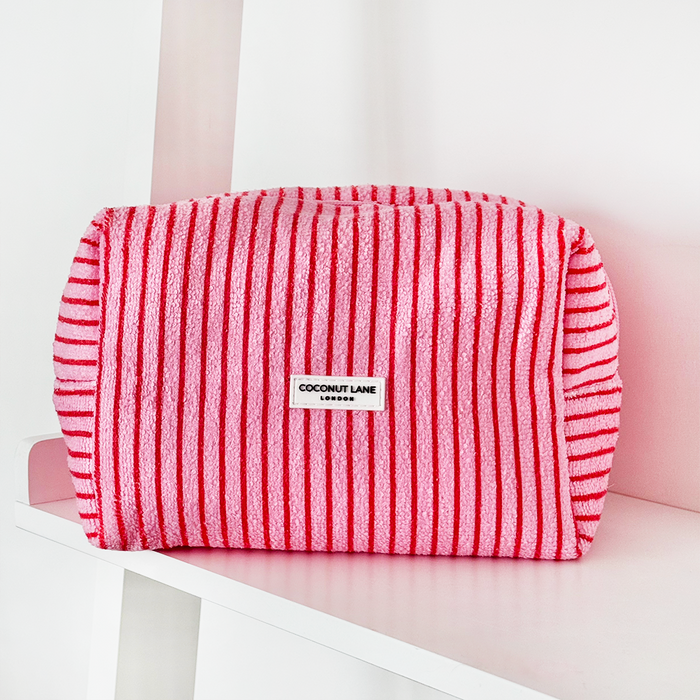 Cherry-striped towel makeup bag with Coconut Lane branding on a white shelf.