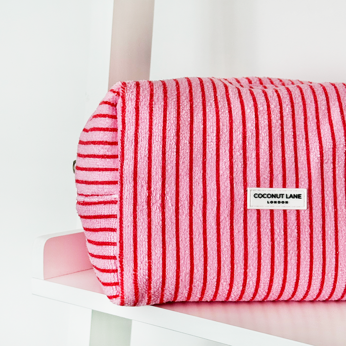 Cherry Stripes Towel Makeup Bag by Coconut Lane with red cherry and stripe pattern on a white shelf.